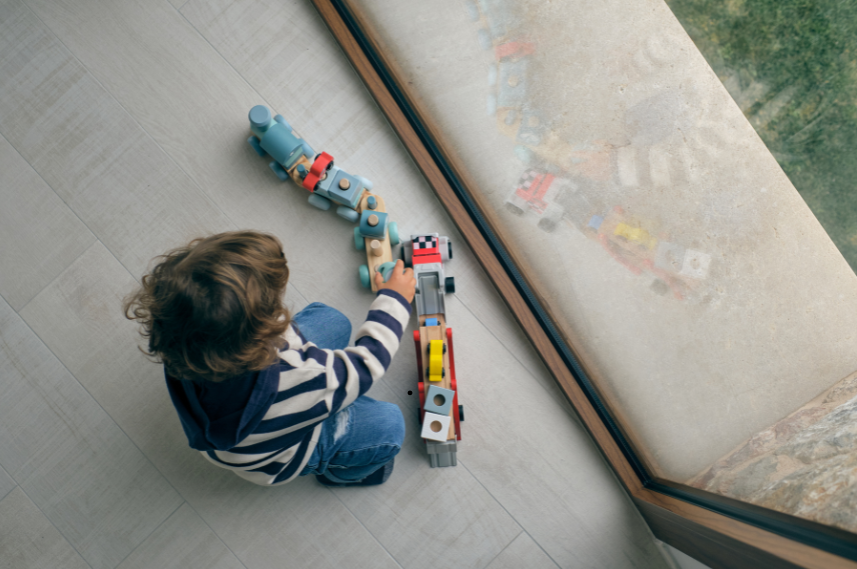 Kind sitzt auf dem Boden und spielt mit einer Spielzeugeisenbahn